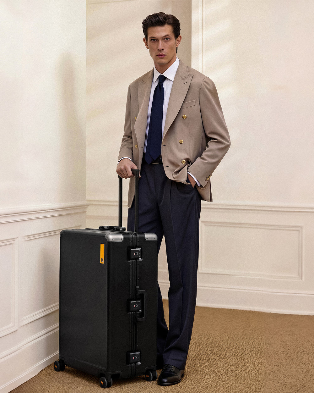 Young man walking with Hegent Checked 28" Black suitcase in front of classical architecture lifestyle scene